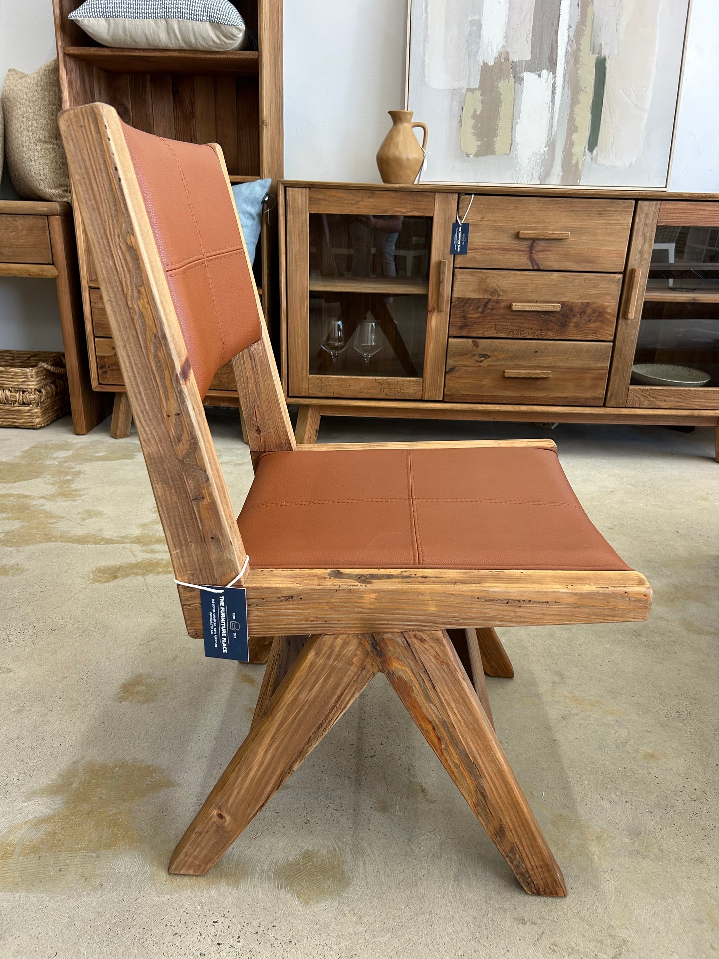 Side view of rustic and farmhouse style dining chair wooden frame with tan leather seat