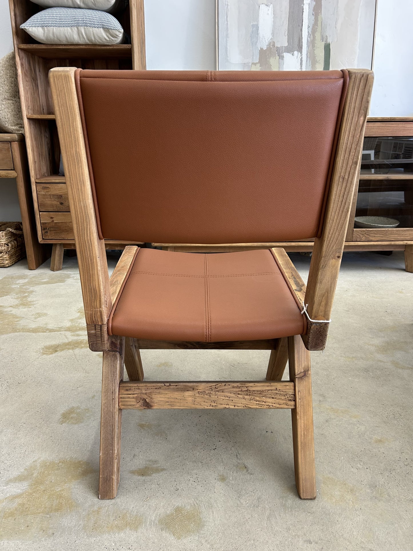 Back view of wooden dining chair with tan leather seat and tan leather backrest