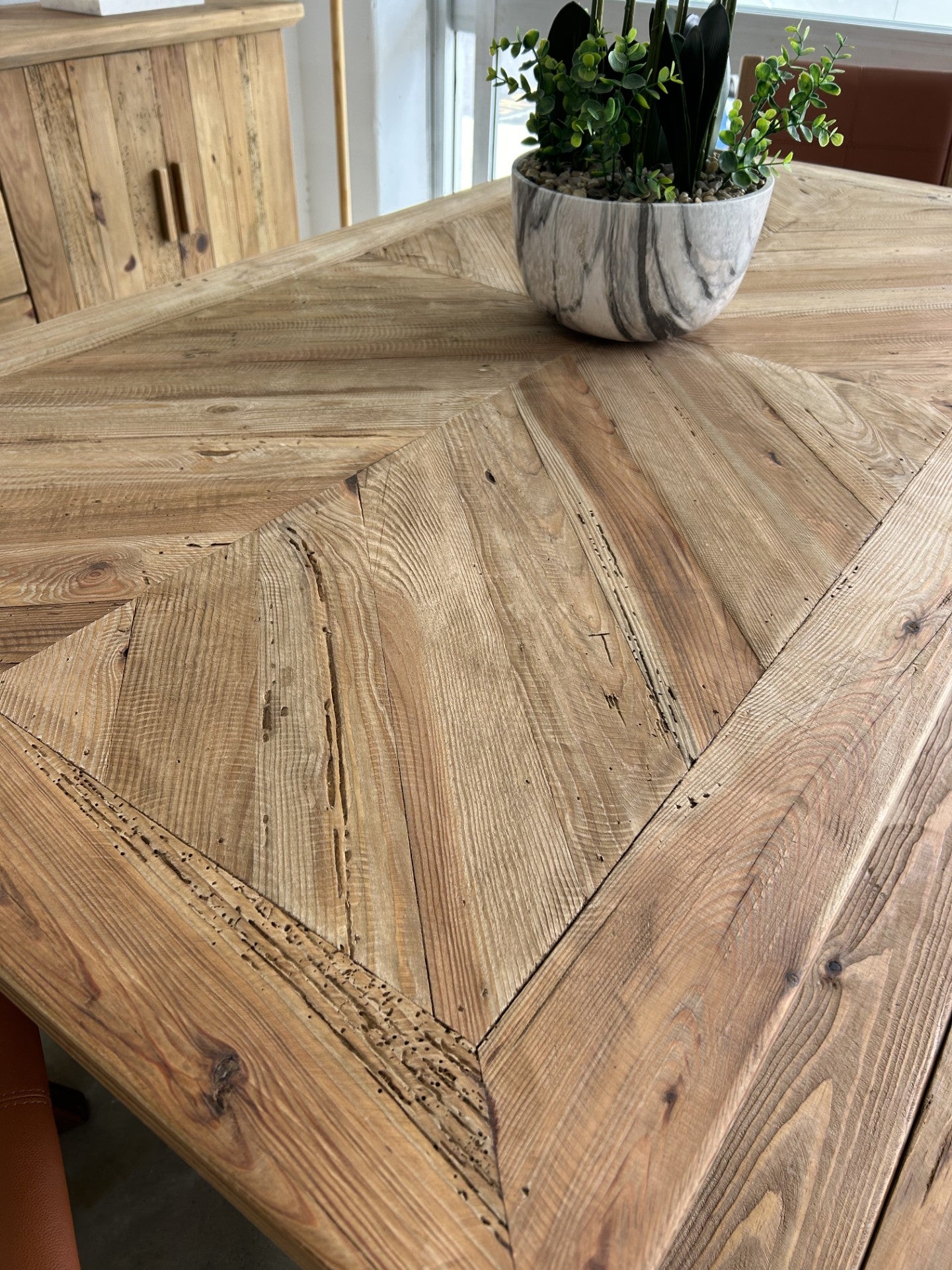 Close up of table top of farmhouse style reclaimed wood dining table which features an angled wood pattern and distressed design