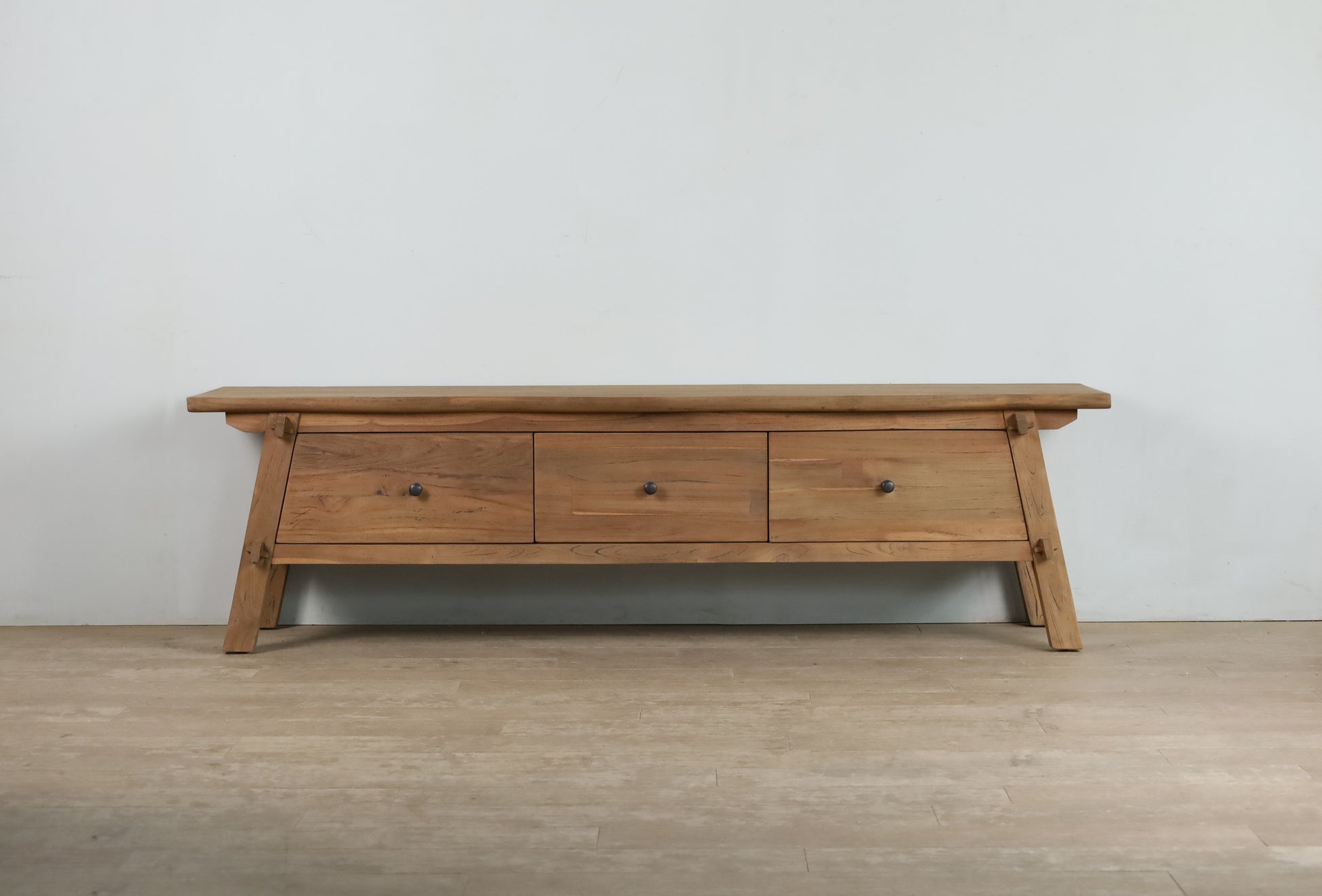 Front view of a dark wood TV unit with trestle legs and 3 drawers