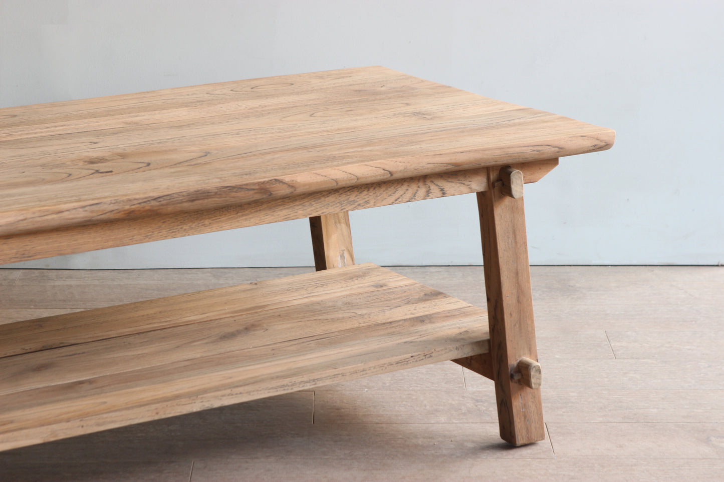 Close up of farmhouse style coffee table made of teak wood with trestle style legs