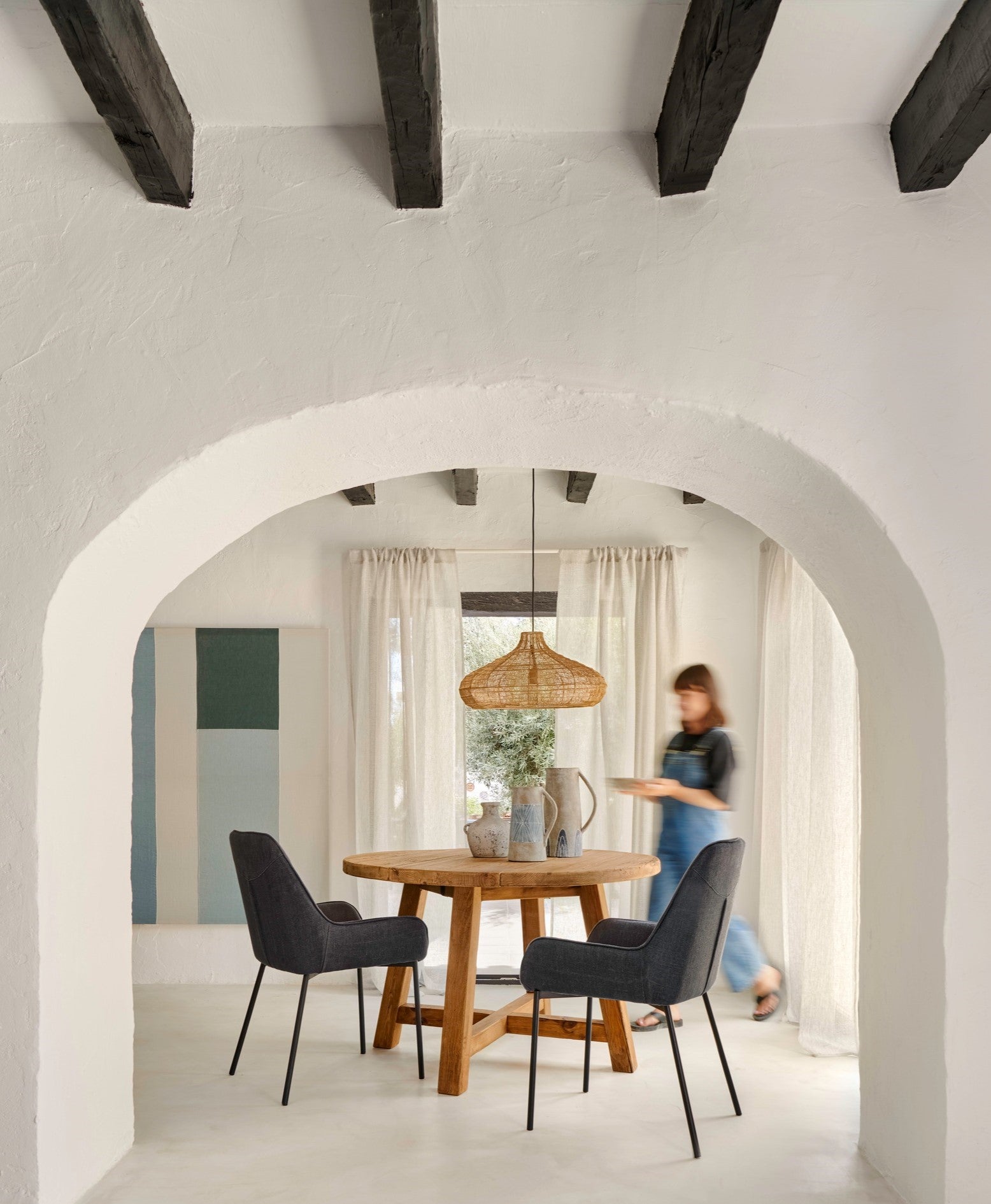 Rustic round dining table with black chairs in a modern home